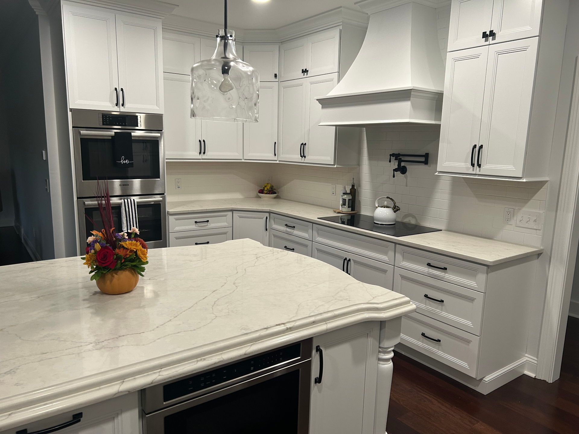 Custom white kitchen with quartz waterfall island and pot-filler