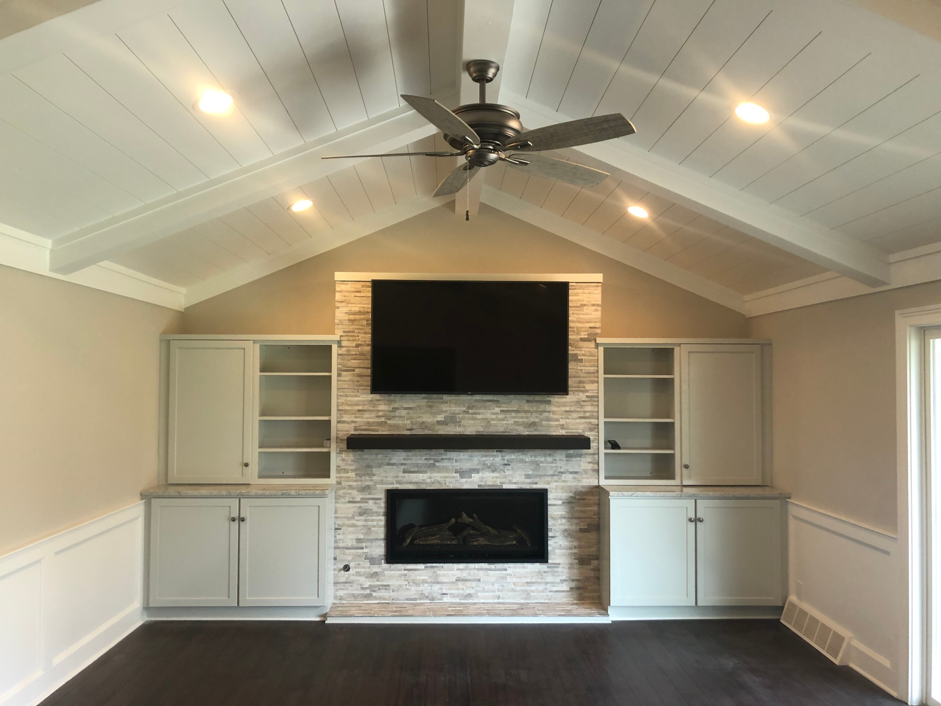 Vaulted shiplap ceiling great room with stone fireplace and built-ins